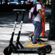Pedestrians walk past electric scooters Thursday, Aug. 8, 2019, in Atlanta.